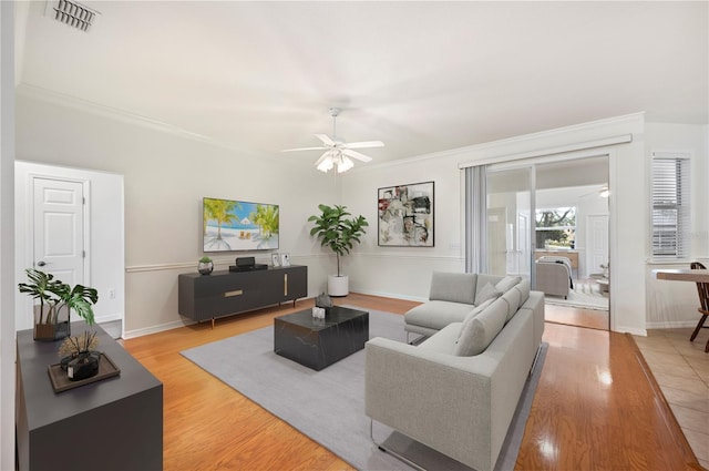 living room featuring light hardwood / wood-style floors, ceiling fan, and crown molding