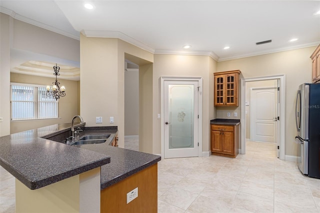 kitchen featuring kitchen peninsula, stainless steel fridge, ornamental molding, sink, and an inviting chandelier