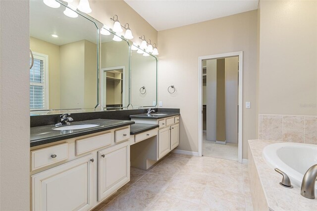 bathroom featuring tile patterned floors, tiled bath, and vanity