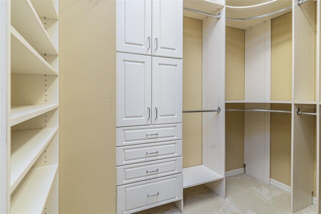 walk in closet featuring light colored carpet