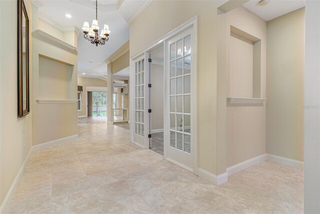 hallway with a notable chandelier, ornamental molding, and french doors