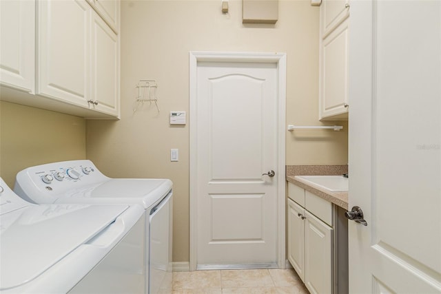 washroom with cabinets, light tile patterned floors, washer and clothes dryer, and sink