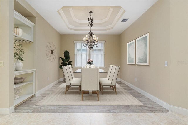 dining space featuring an inviting chandelier, a raised ceiling, and ornamental molding