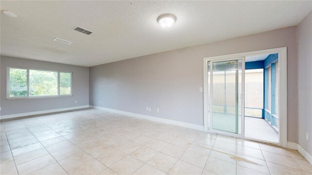 unfurnished room featuring a textured ceiling and light tile floors