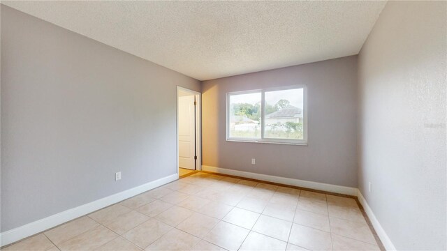 tiled empty room featuring a textured ceiling