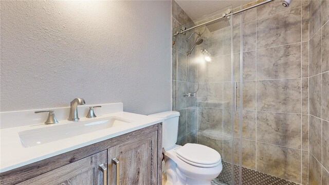 bathroom featuring tiled shower, vanity, and toilet