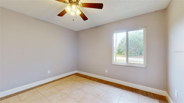 spare room featuring a textured ceiling, ceiling fan, and light tile floors