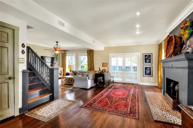 entrance foyer featuring dark hardwood / wood-style flooring, a fireplace, ceiling fan, ornamental molding, and french doors