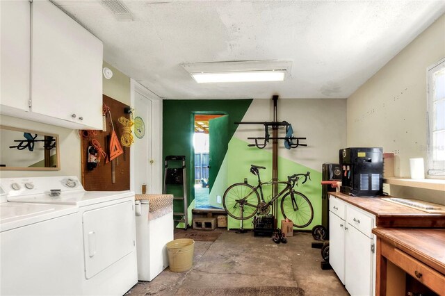 laundry room featuring washer and dryer, a textured ceiling, and cabinets