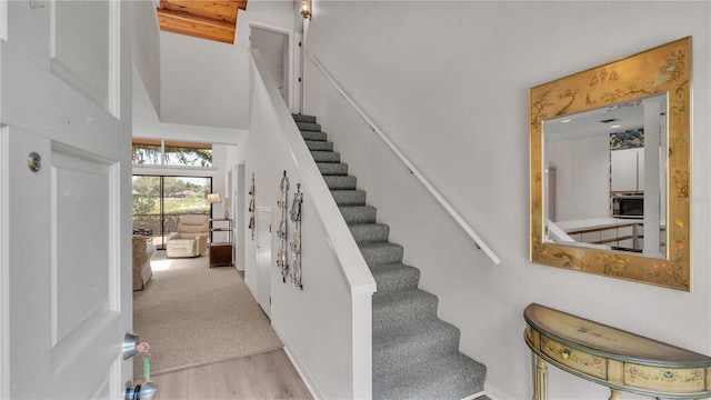 staircase with a towering ceiling and wood-type flooring