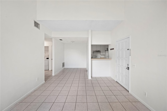 spare room featuring washer / dryer and light tile patterned floors