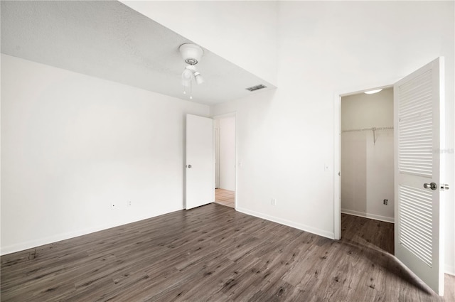 unfurnished bedroom featuring a closet, a spacious closet, ceiling fan, and hardwood / wood-style floors