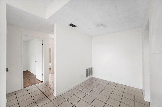 tiled empty room with a textured ceiling