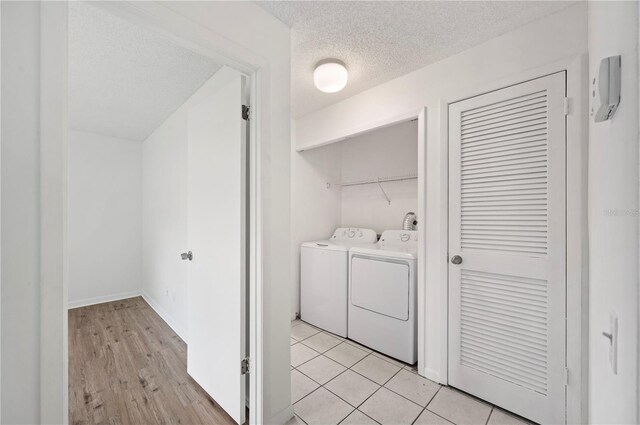 laundry area featuring washer and clothes dryer, a textured ceiling, and light hardwood / wood-style floors