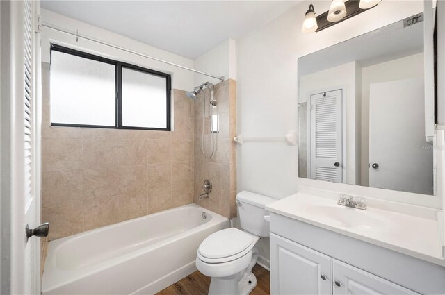 full bathroom with tiled shower / bath combo, hardwood / wood-style floors, vanity, and toilet