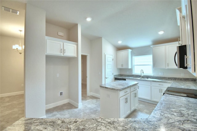 kitchen featuring a center island, white cabinets, sink, light stone countertops, and a notable chandelier