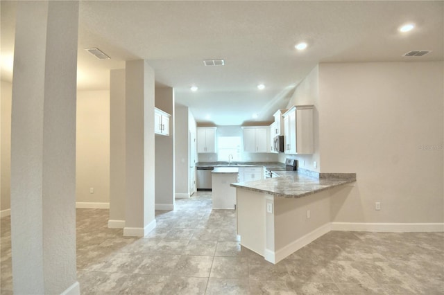 kitchen featuring sink, light stone counters, kitchen peninsula, white cabinets, and appliances with stainless steel finishes