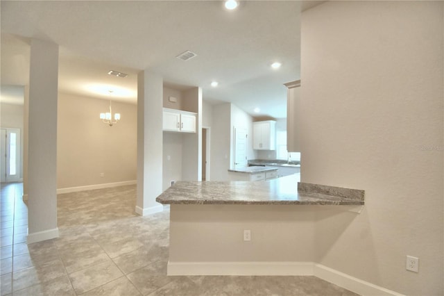 kitchen with kitchen peninsula, white cabinetry, hanging light fixtures, and light stone counters