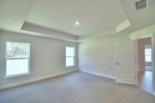 carpeted empty room with a tray ceiling