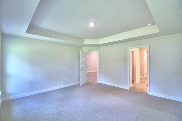 carpeted empty room with a tray ceiling