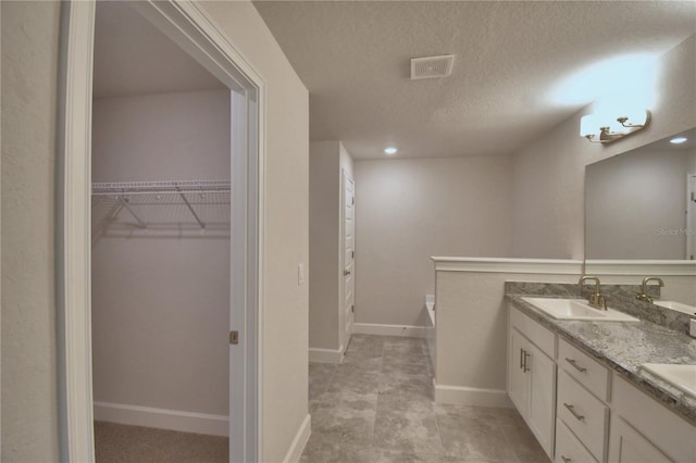 bathroom featuring a tub to relax in, vanity, and a textured ceiling