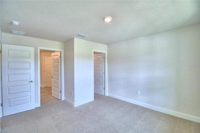 unfurnished bedroom with light colored carpet and a textured ceiling