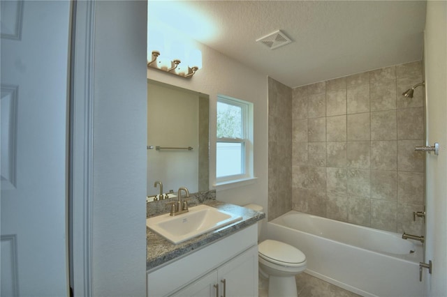 full bathroom with a textured ceiling, vanity, toilet, and tiled shower / bath combo