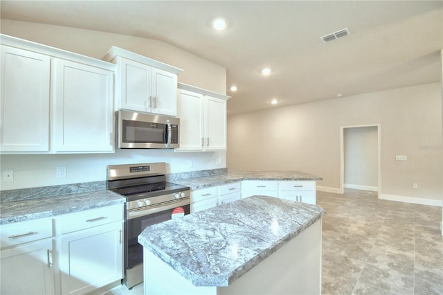 kitchen with light stone countertops, a center island, white cabinets, and appliances with stainless steel finishes