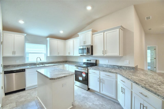 kitchen featuring lofted ceiling, sink, appliances with stainless steel finishes, light stone counters, and white cabinetry