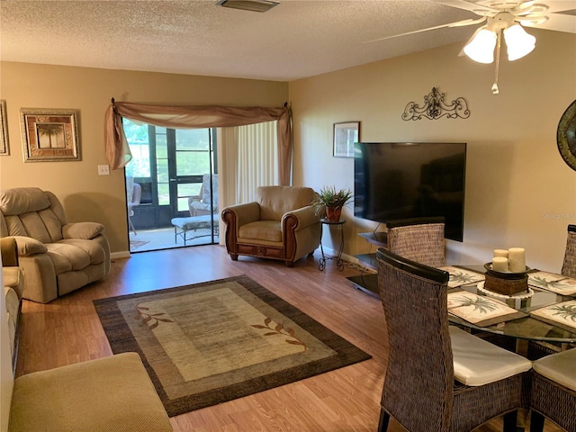 living room with a textured ceiling, ceiling fan, and hardwood / wood-style floors