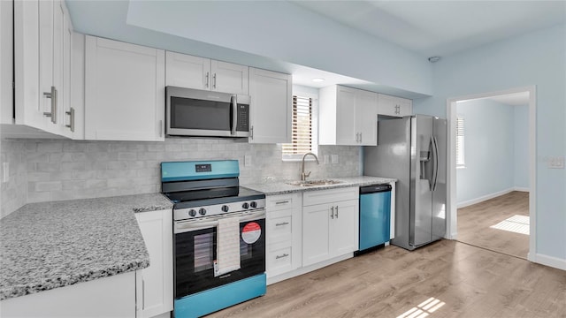 kitchen with light stone counters, sink, white cabinets, and appliances with stainless steel finishes