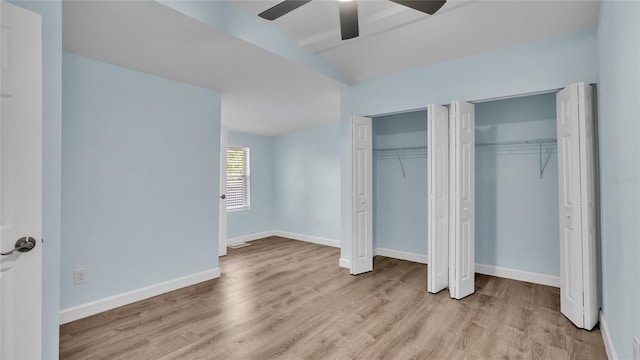 unfurnished bedroom with two closets, light hardwood / wood-style flooring, and ceiling fan