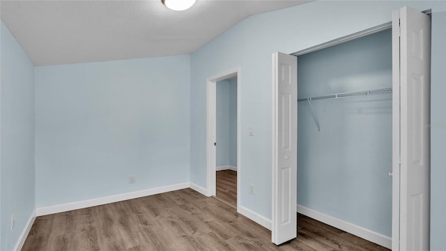 unfurnished bedroom featuring lofted ceiling, light hardwood / wood-style flooring, and a closet