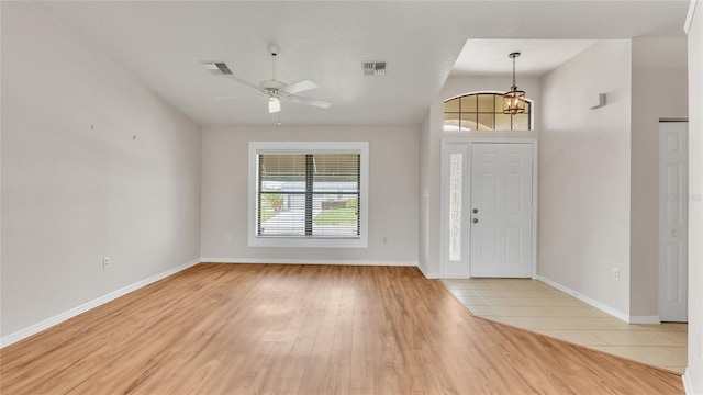 foyer entrance with light tile patterned floors, ceiling fan with notable chandelier, and lofted ceiling