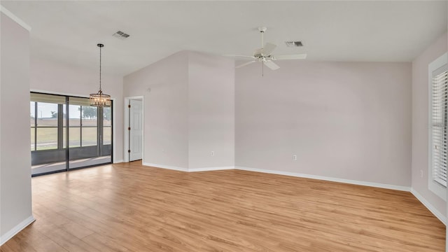 empty room featuring vaulted ceiling, ceiling fan with notable chandelier, and light wood-type flooring