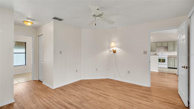 empty room featuring a textured ceiling, light hardwood / wood-style floors, and ceiling fan