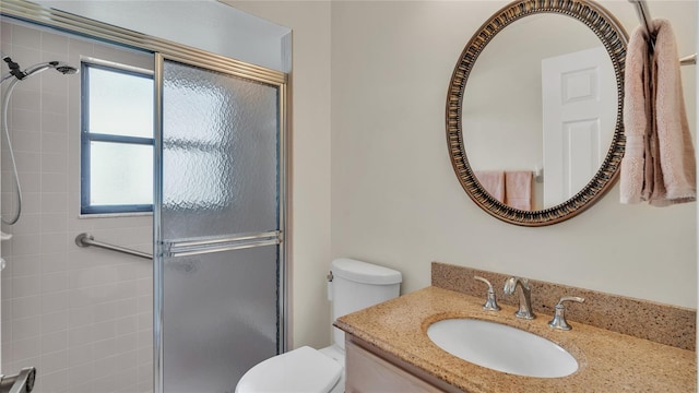 bathroom with a shower with door, vanity, and toilet