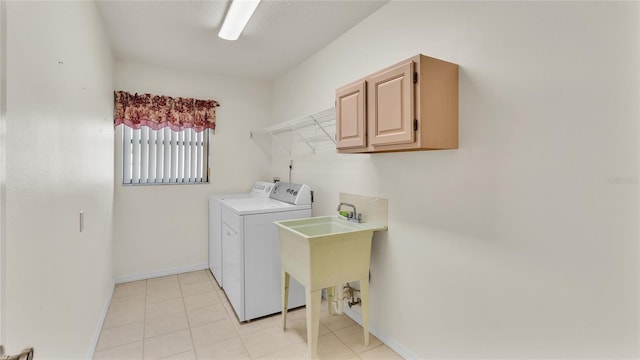 clothes washing area featuring washer and clothes dryer, light tile patterned floors, cabinets, and sink