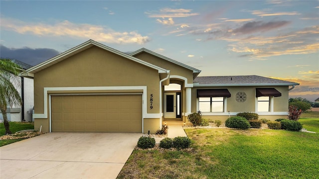 ranch-style home featuring a garage and a yard