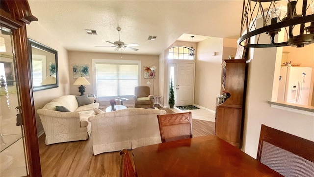 living room with ceiling fan, a textured ceiling, and light wood-type flooring