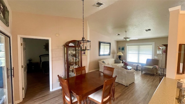 dining space with ceiling fan, wood-type flooring, a textured ceiling, and vaulted ceiling