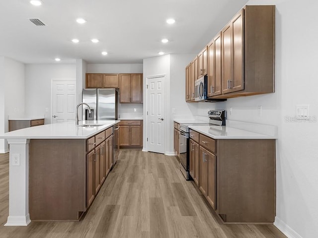 kitchen featuring a center island with sink, light hardwood / wood-style floors, sink, and appliances with stainless steel finishes