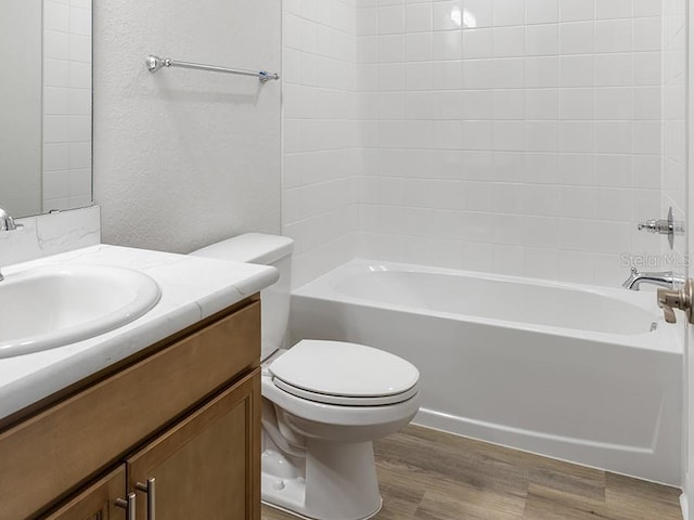 full bathroom with hardwood / wood-style floors, tiled shower / bath combo, toilet, and vanity