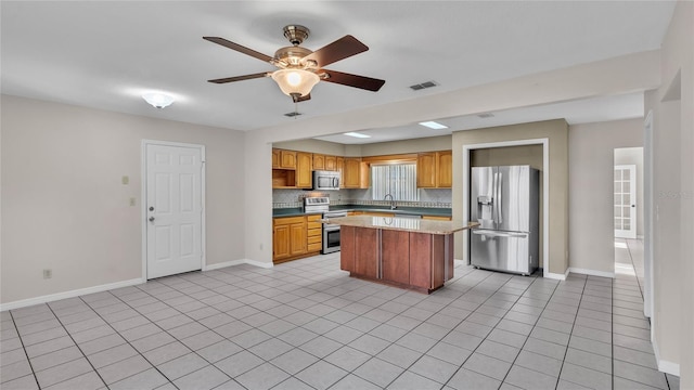 6110 Downing St, Dover, FL 33527 - kitchen featuring appliances with stainless steel finishes, a kitchen island, decorative backsplash, light tile patterned flooring, and a ceiling fan