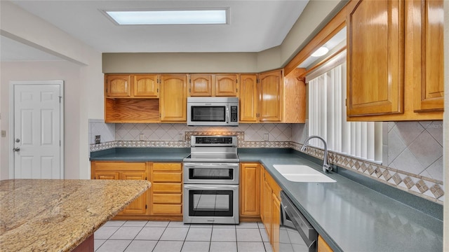 kitchen featuring backsplash, light tile patterned floors, sink, and appliances with stainless steel finishes