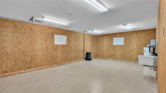 basement with a textured ceiling and water heater