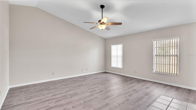 empty room with ceiling fan, vaulted ceiling, and light hardwood / wood-style flooring