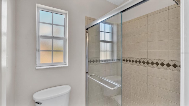 bathroom featuring a shower with shower door and toilet