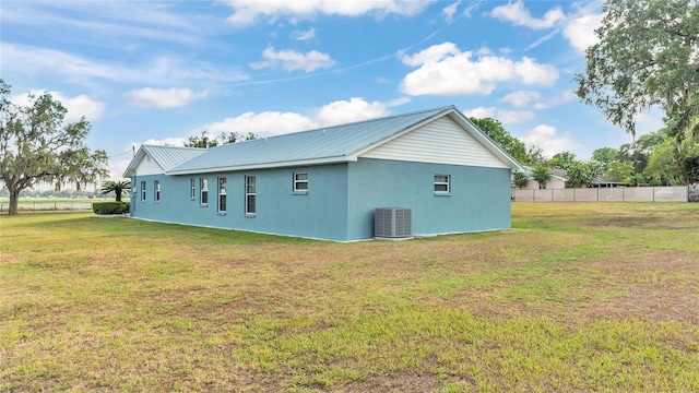 view of side of property featuring a lawn and central AC