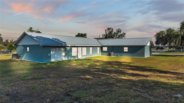 back house at dusk with a yard and cooling unit